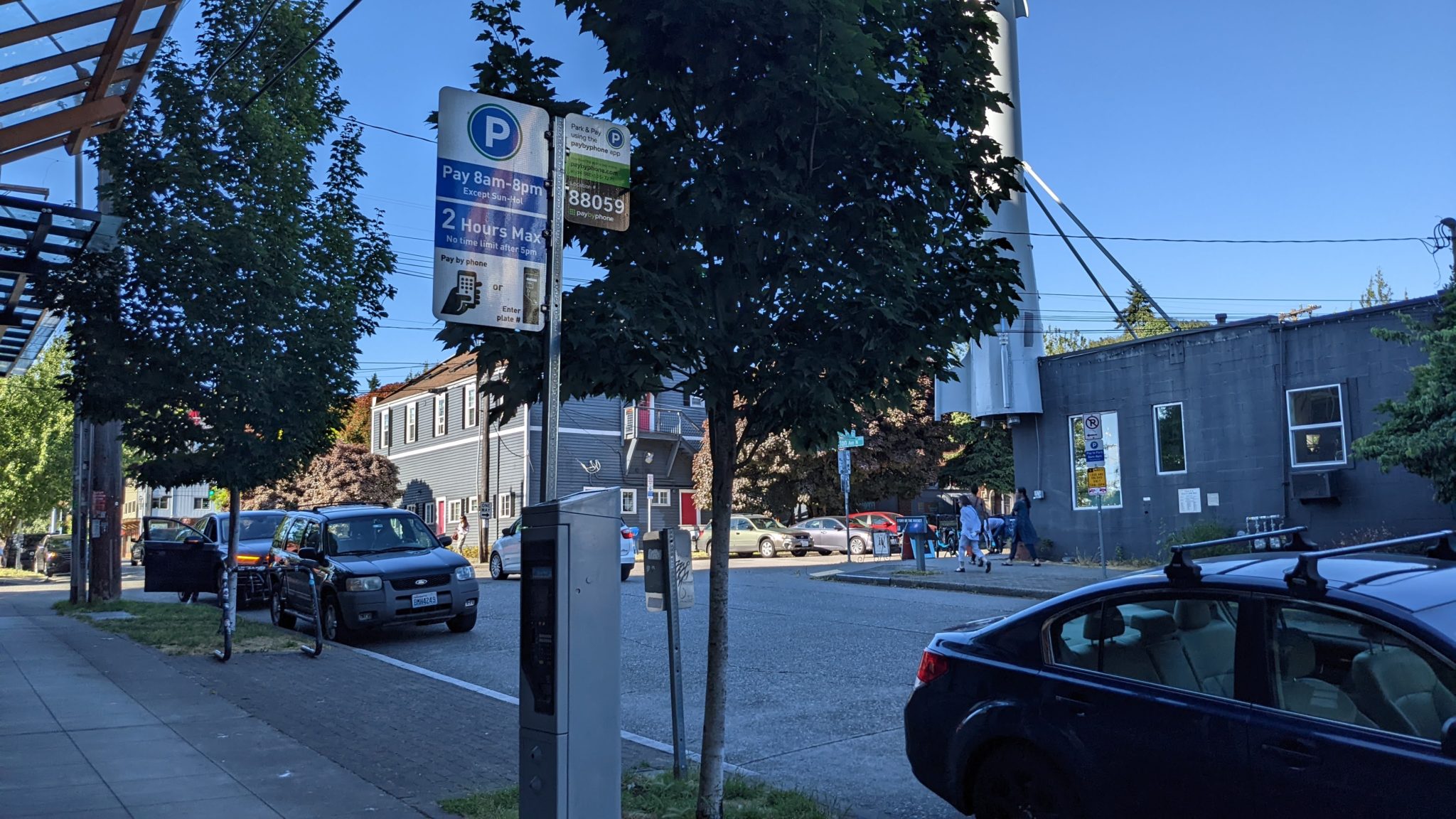Parked cars on the street in Seattle's Fremont neighborhood. Several parked cars are located next to paid parking signs, trees, and buildings in the area..