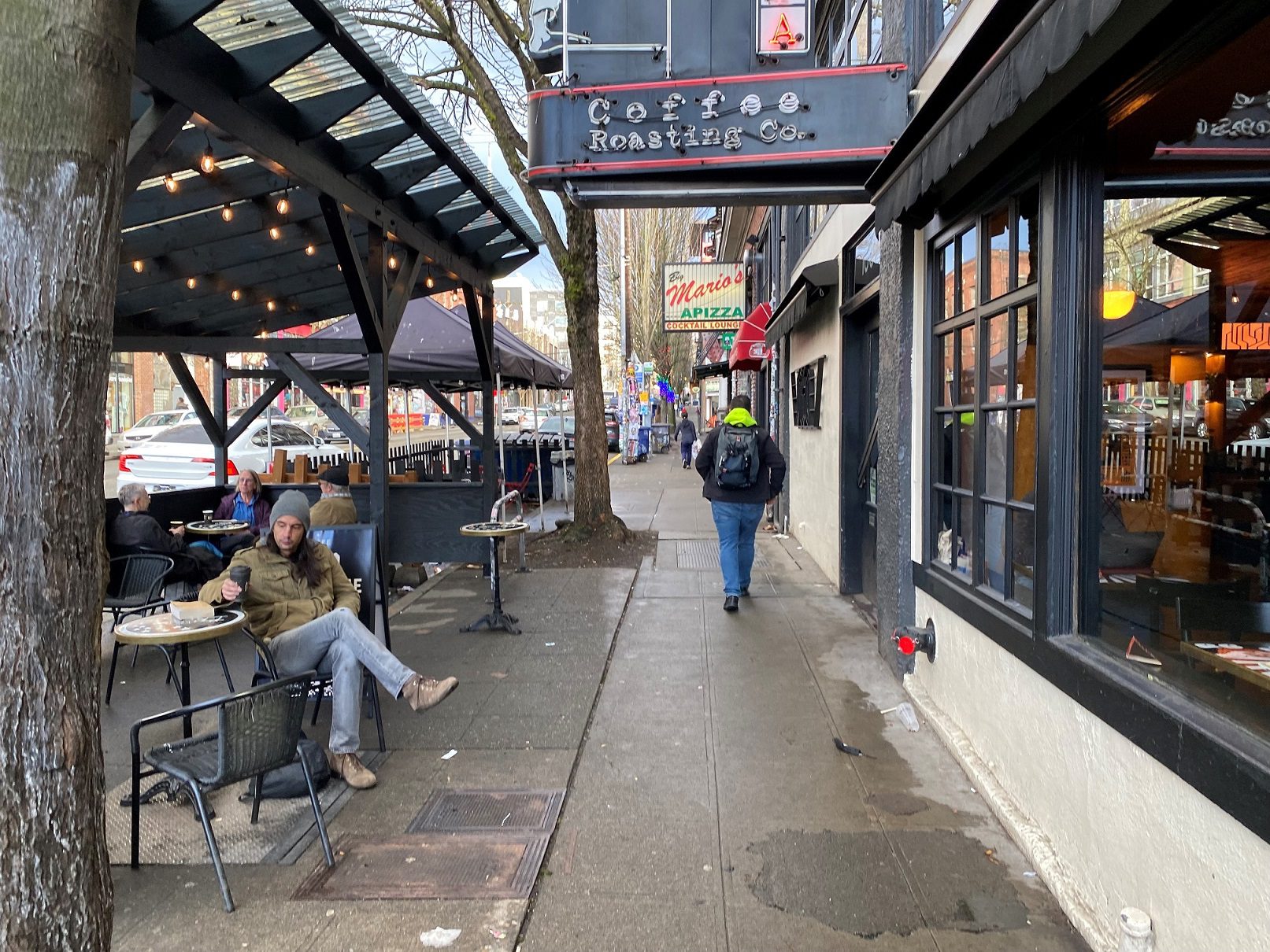 Outdoor dining and coffee-sipping space in Seattle’s Capitol Hill neighborhood. A person can be seen sitting while drinking a coffee, as another person walks down the sidewalk.