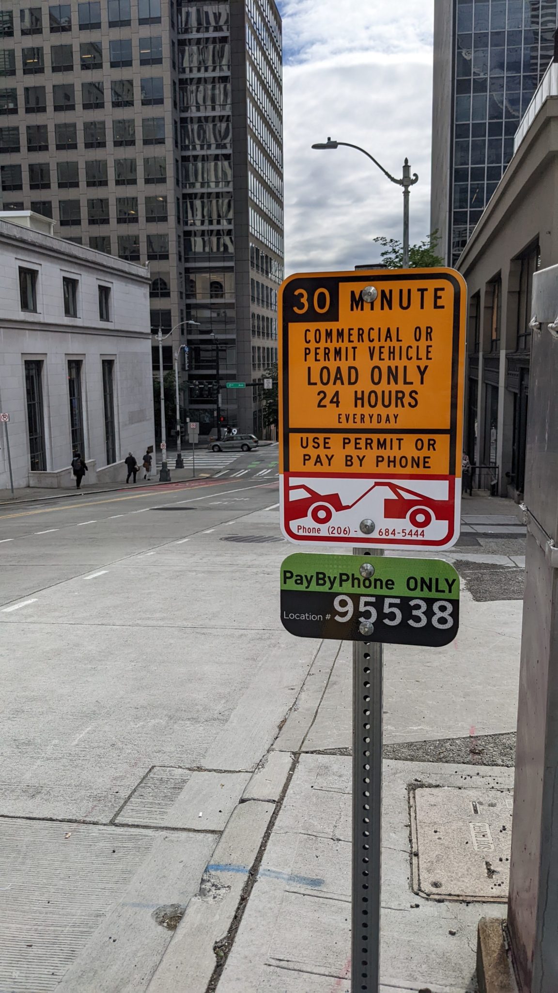 A Commercial Vehicle Load Zone sign in downtown Seattle. Wording notes to commercial drivers that they can pay by phone, with a location identifying number shown on the sign.