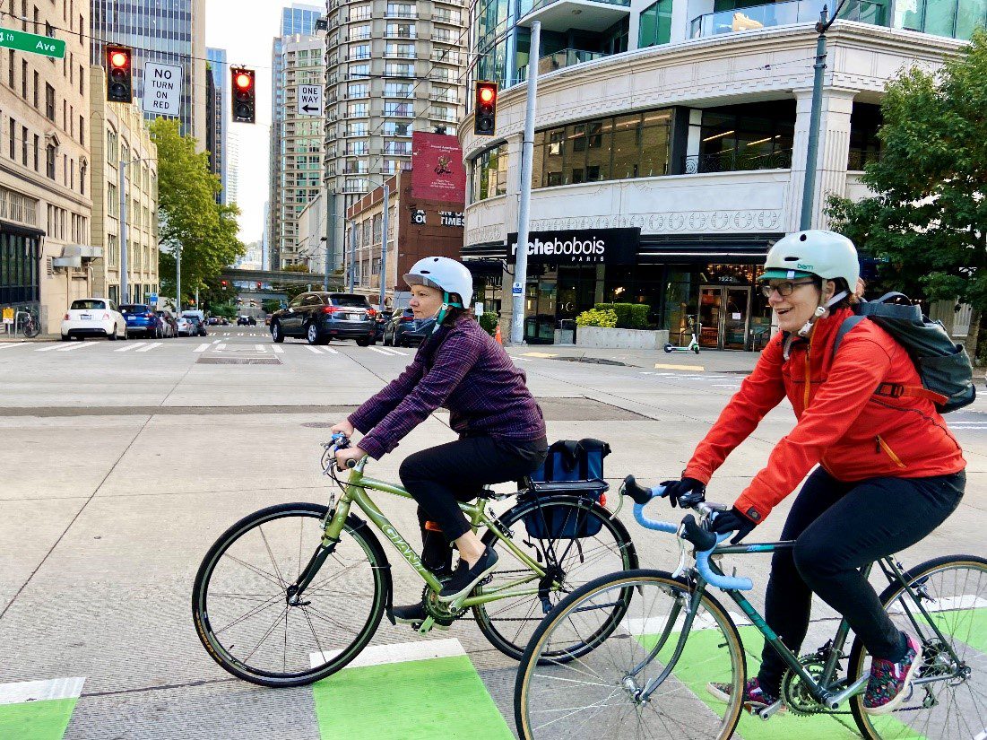 Two people bike in the protected bike lane on 4th Avenue in downtown Seattle. 