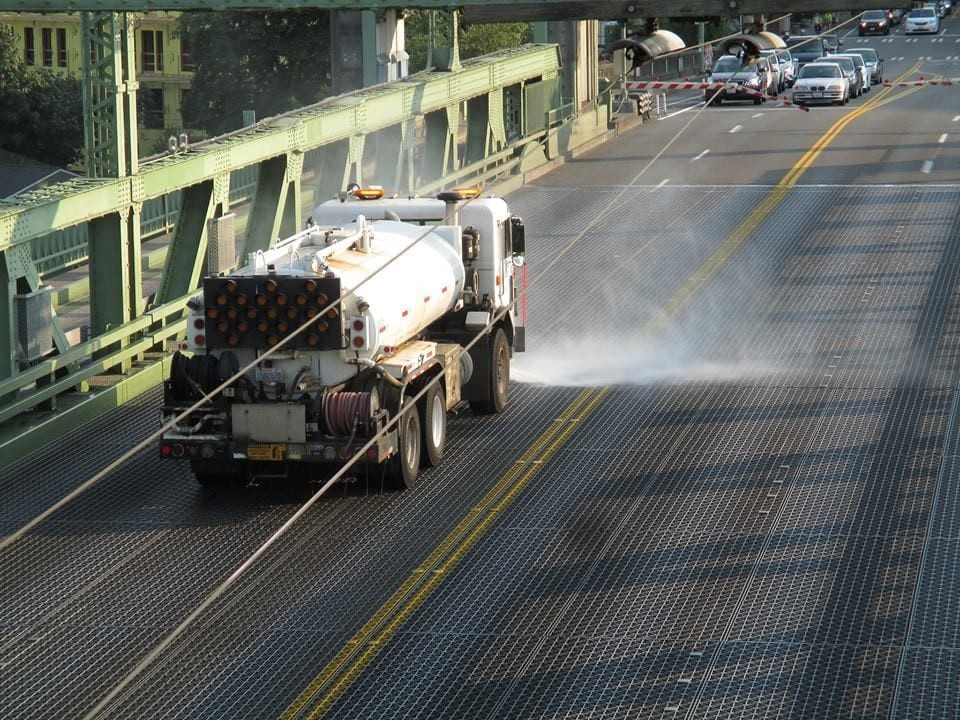 Image of an SDOT truck spraying down a bridge with water.