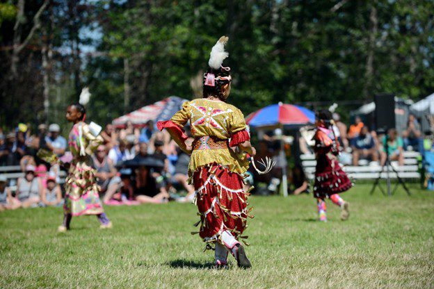 Three people dance at a past Powwow.