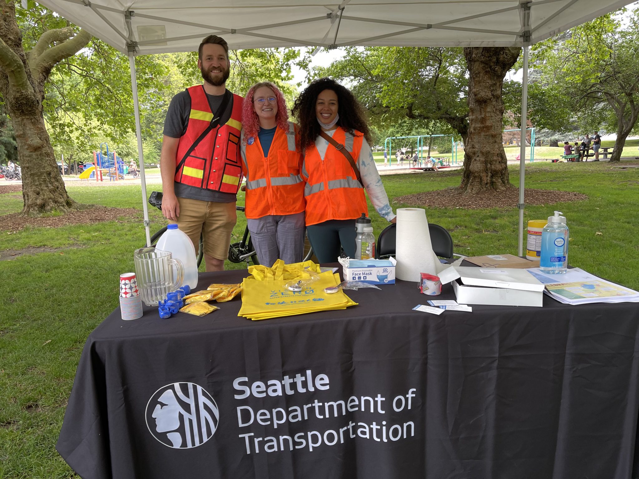 Members of the SDOT team smile while tabling at a past community event in a city park.