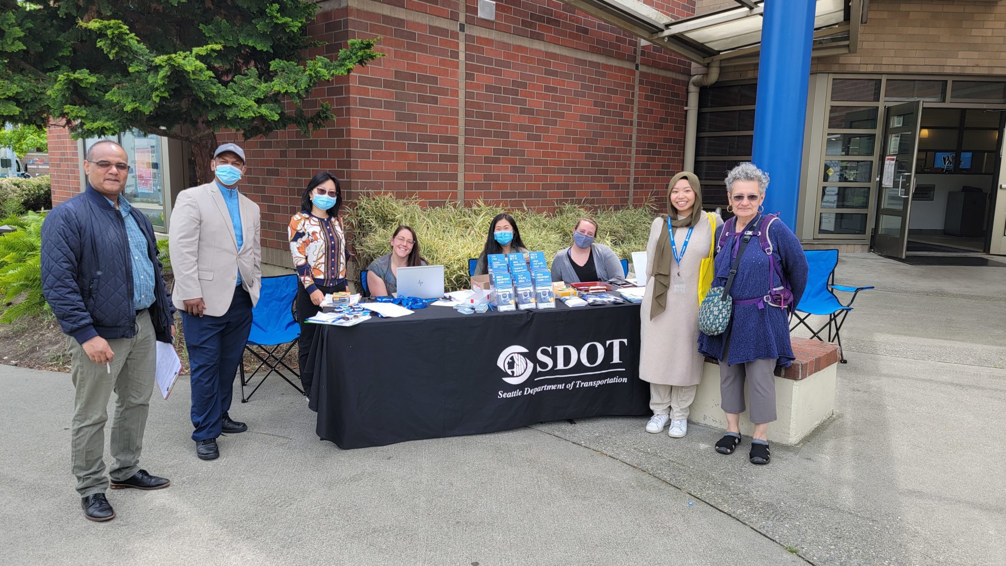 We partnered with Community Liaisons to get out the word about Recovery cards! Photo of community members and City of Seattle staff smiling at a recent outreach event, with an SDOT table located in the middle.
