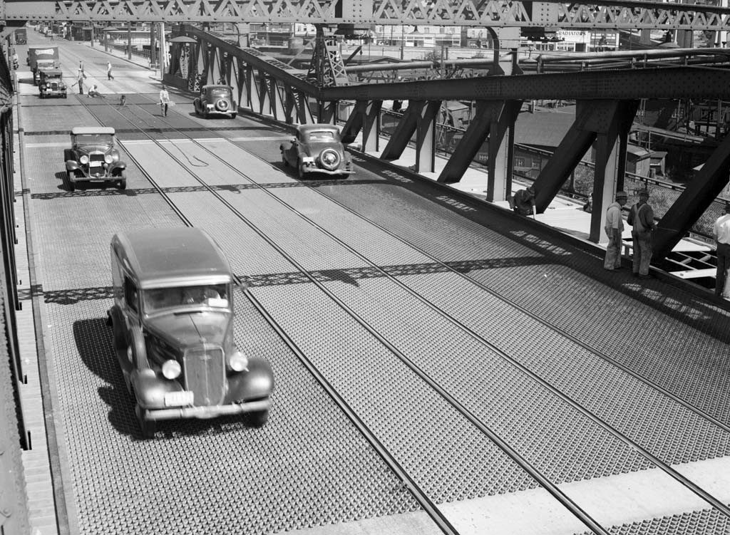 Black and white photo of the Fremont bridge, with a cars traveling across the bridge in both directions.  