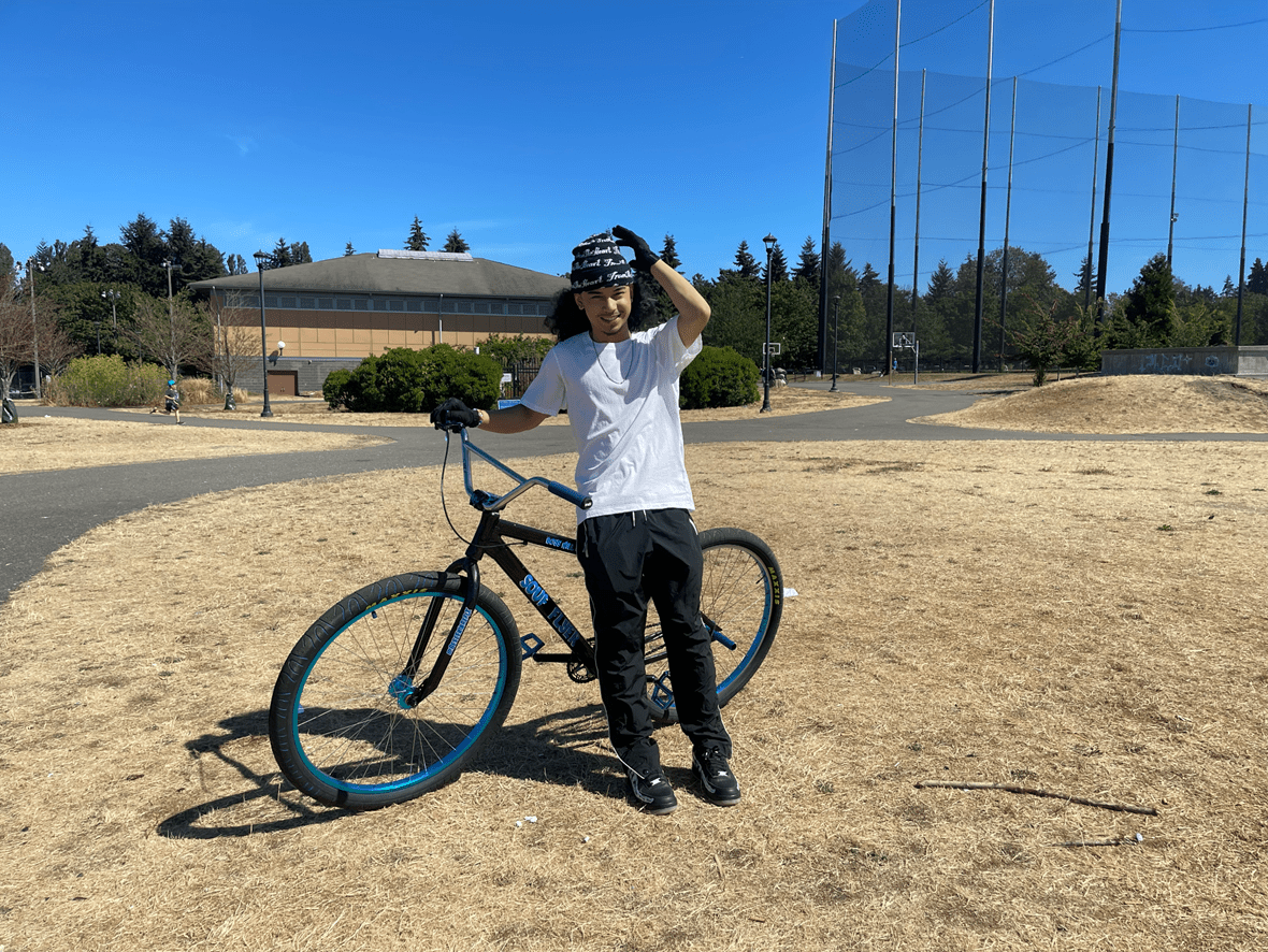 Person standing by a bicycle in the middle of a grassy area.