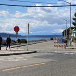 People walk along the entrance to the Alki Point Healthy Street on a sunny and cloudy day.