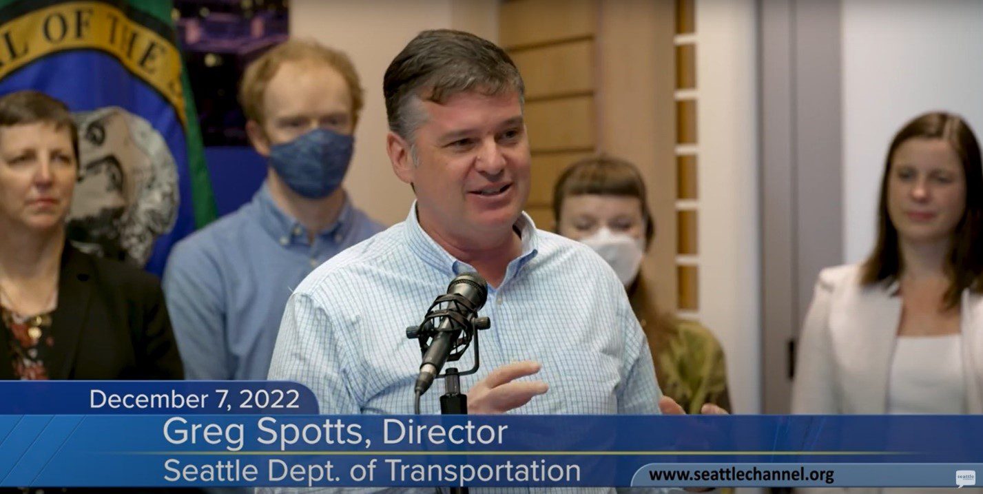 SDOT Director Greg Spotts speaks in front of cameras at a recent executive order signing event. People stand behind Greg while watching his remarks.