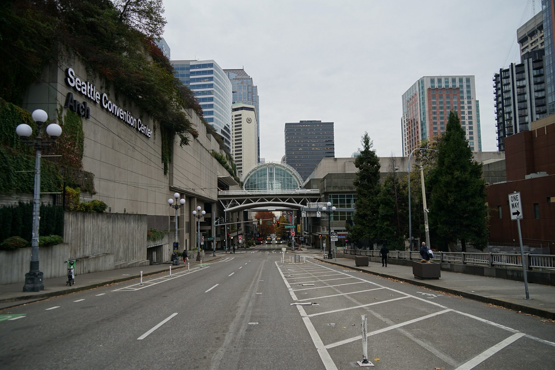 View of a street with large buildings in the background on a cloudy day.