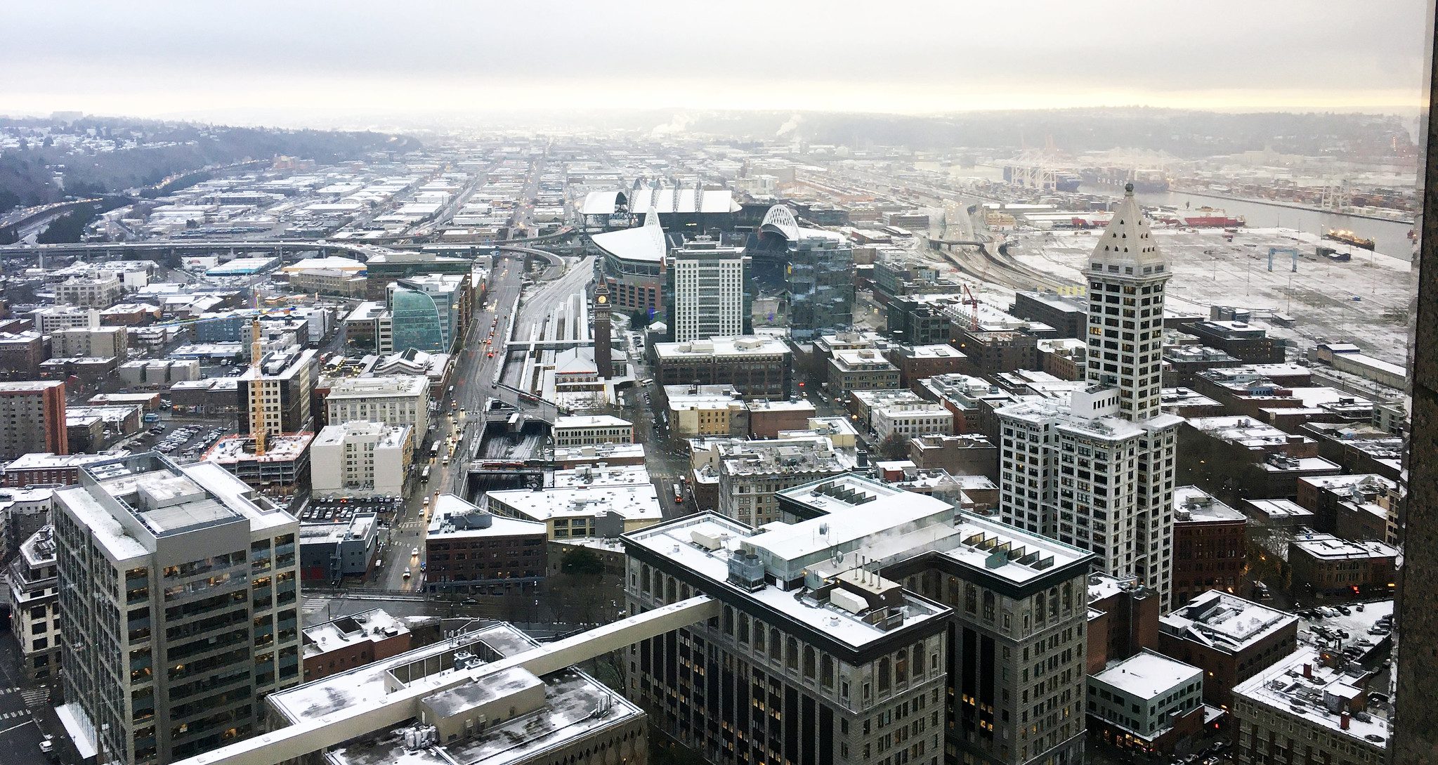 A view of the city on a wintery day. Large buildings and a stadium are visible, and clouds are above.