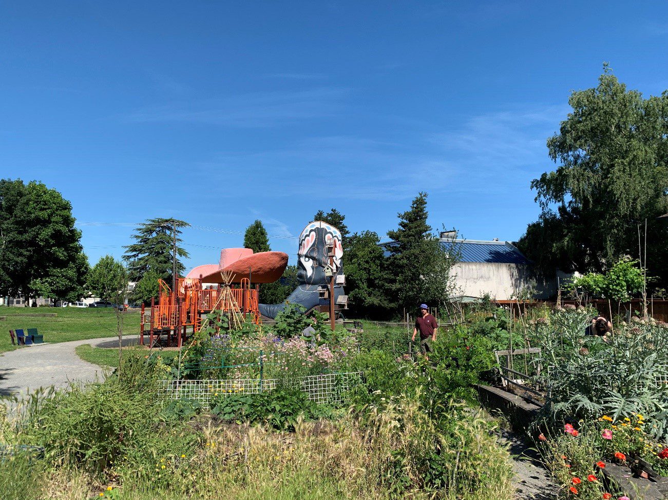 A person walking among plants and tall grasses on a sunny day. In the background is a large cowboy hat and boot statue.