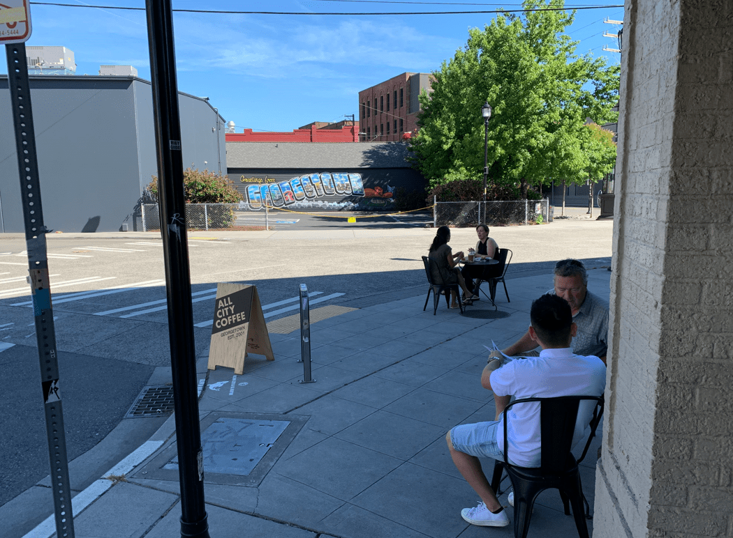 Two groups of two people sit outside All City Coffee in Georgetown.