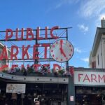 A photo of the Pike Place Public Market neon sign, angled upward toward a clear blue sky.