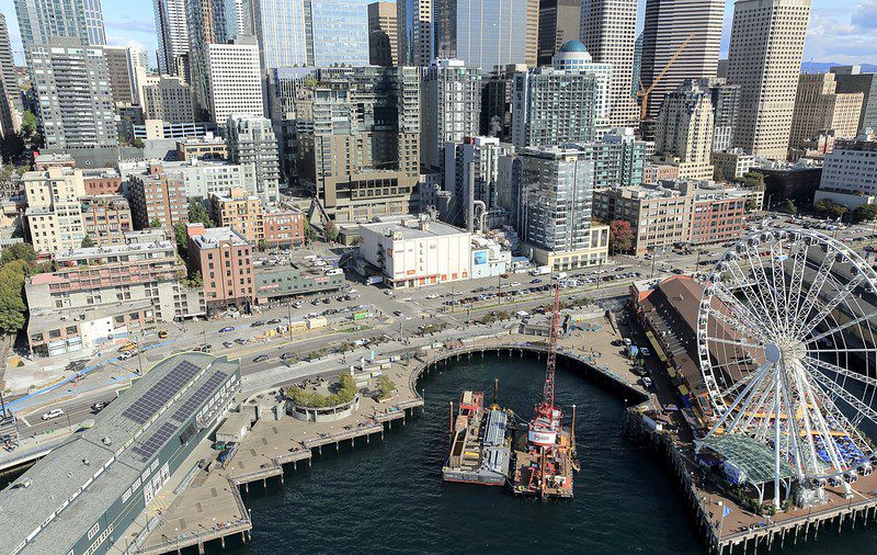 An aerial photo showing the central waterfront after the demolition of the viaduct. Crews can be seen doing work on the waterfront pathway between the Seattle Aquarium and the Great Wheel.