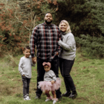 A man, woman, and two children stand together in an outdoor nature area.