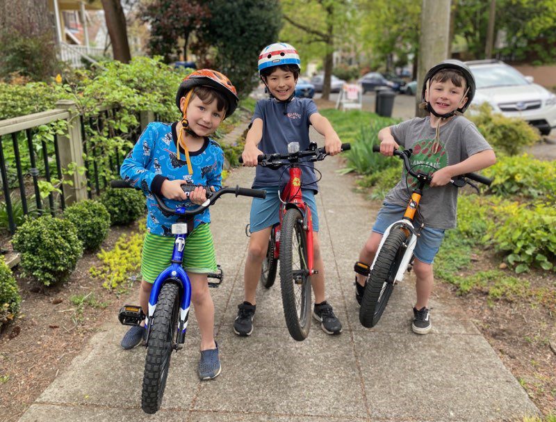 Three youngsters smile while riding their bikes in Seattle. Photo credit: Jeanné Clark 