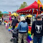 Community members kick off Pride Month at the White Center Pride Street Festival. People lined up next to a red tent on the right.