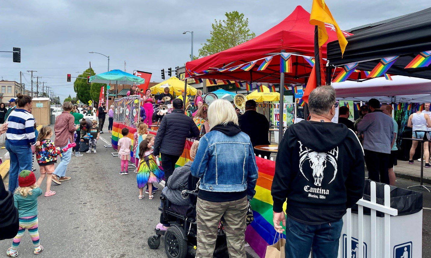 Community members kick off Pride Month at the White Center Pride Street Festival. People lined up next to a red tent on the right.