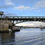 View of a bridge on a mostly sunny day with water at the bottom of the image.