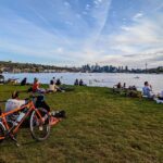 People lounge at Gas Works Park, looking south over Lake Union toward the Seattle skyline.