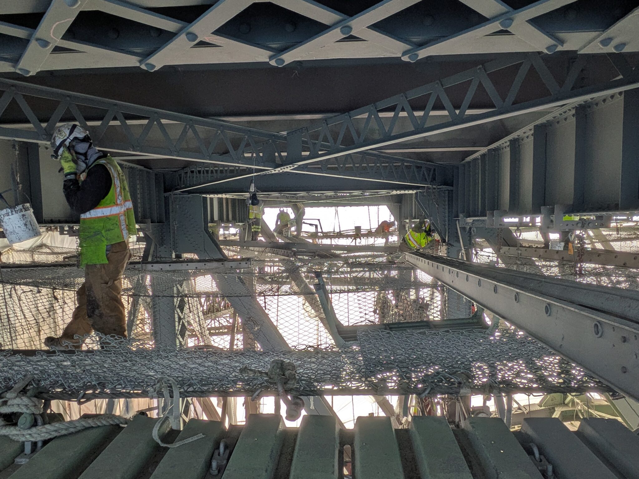 Several people work below a bridge.