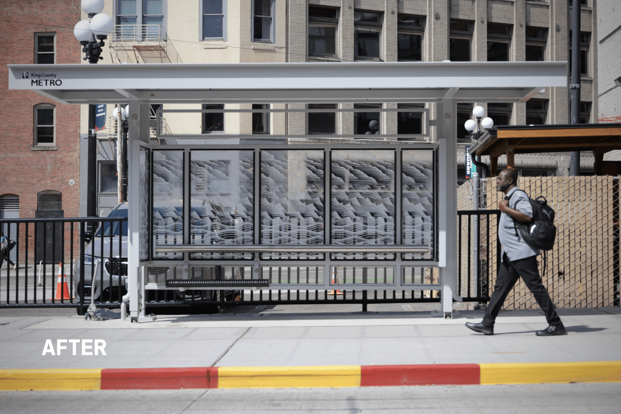 A modern glass-and-metal bus shelter stands along a city sidewalk, with a person walking past in the foreground and buildings lining the street behind it. Bright daylight, colorful curb paint, and the “after” label suggest this image shows an upgraded transit stop in a clean, active urban setting.