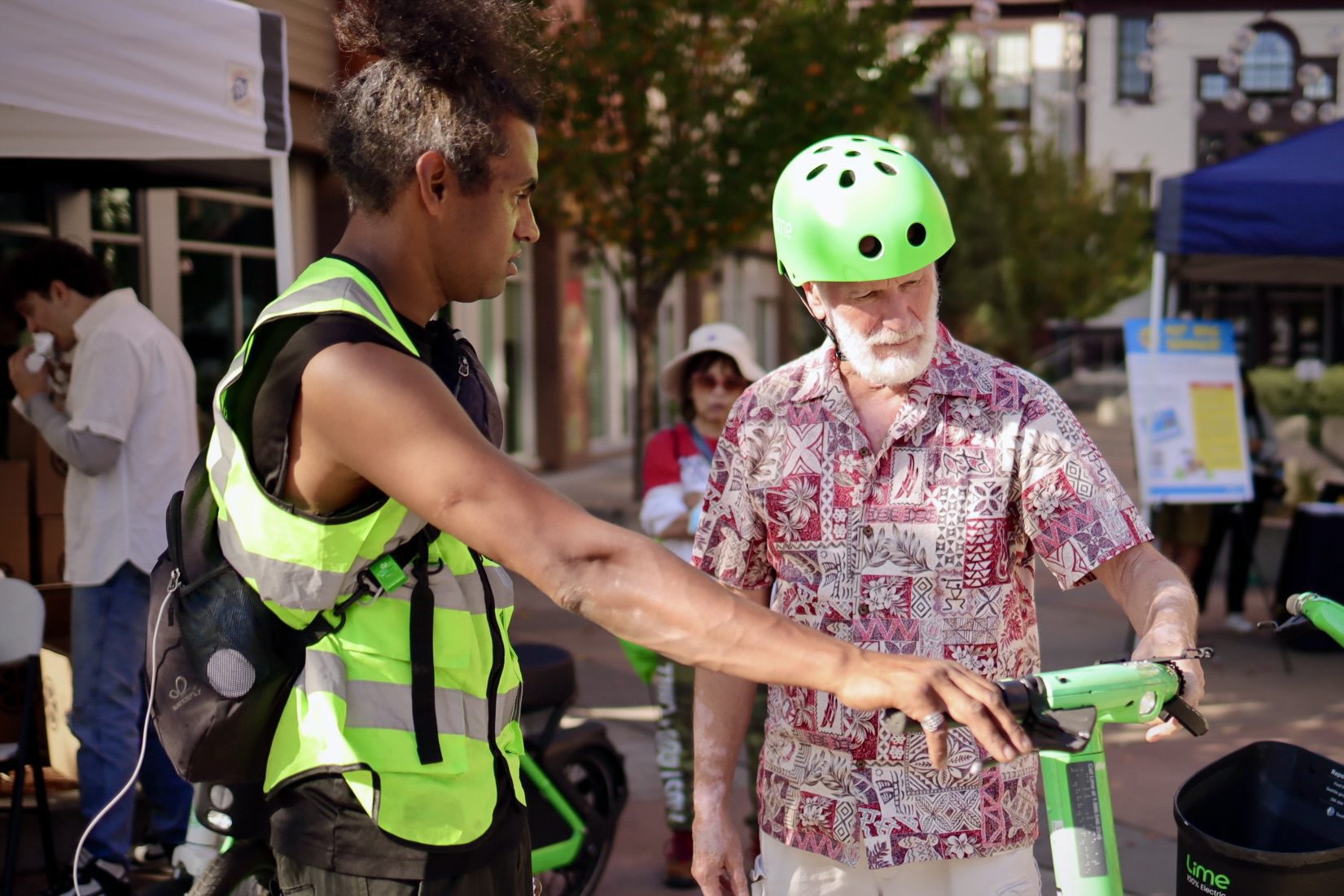 A Lime safety instructor showing a person how to operate a scooter properly.