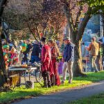 A large group of people gather at an outdoor event on a sunny fall day, many of the people are wearing costumes.